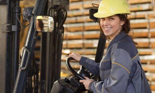 Woman,Industrial,Worker,In,Gray,Uniform,And,Yellow,Helmet,Driving